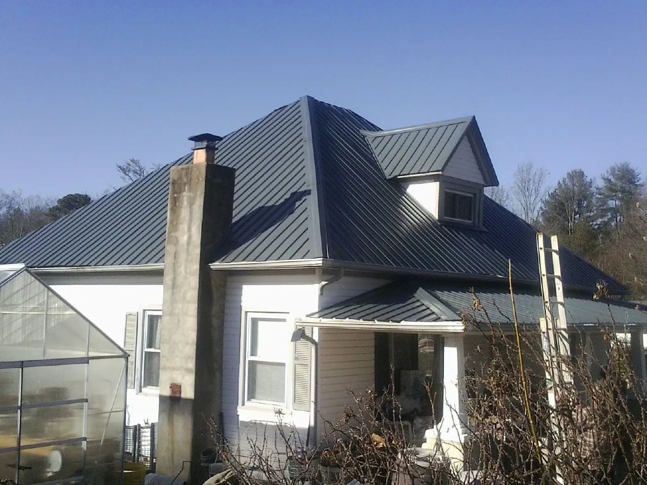 Dark blue standing seam metal roof on a white farmhouse with dormer — Slate & Tile Roof Repair by Roofing Brothers in Pacific