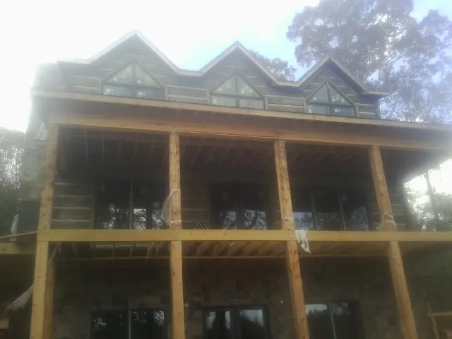 Dormers and porch framing on a large log home under construction — Roof Coating work by our crew in Pacific