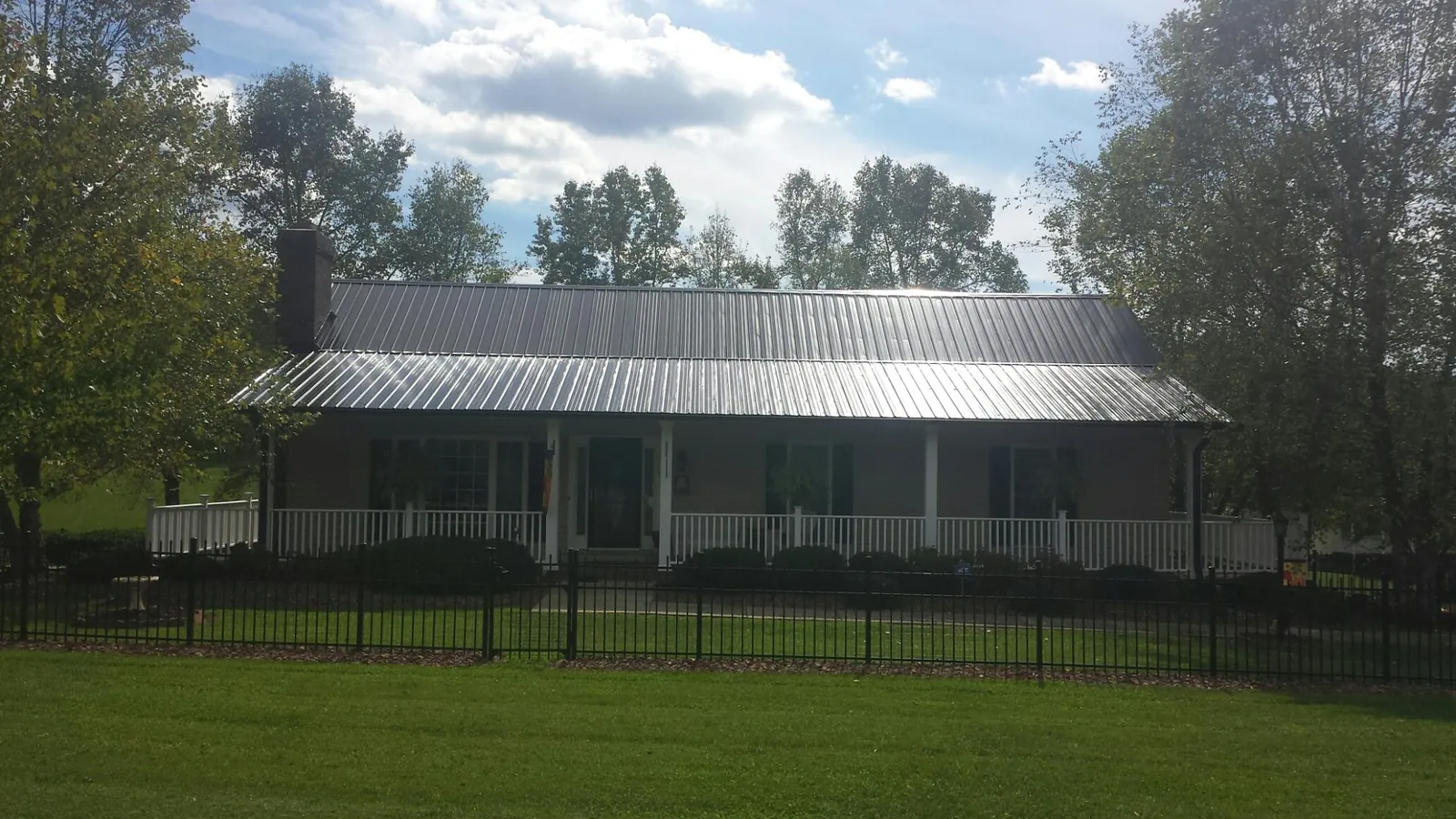 Gray metal roof on a brick ranch with a full width front porch — Gutter Guard Installation work by our crew in Pacific