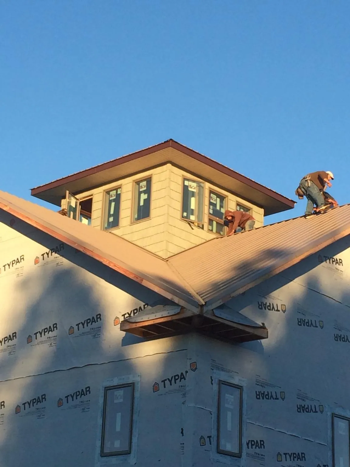 Roofers working around a rooftop cupola on a new metal roof at sunset — Roof Waterproofing in Pacific by Roofing Brothers